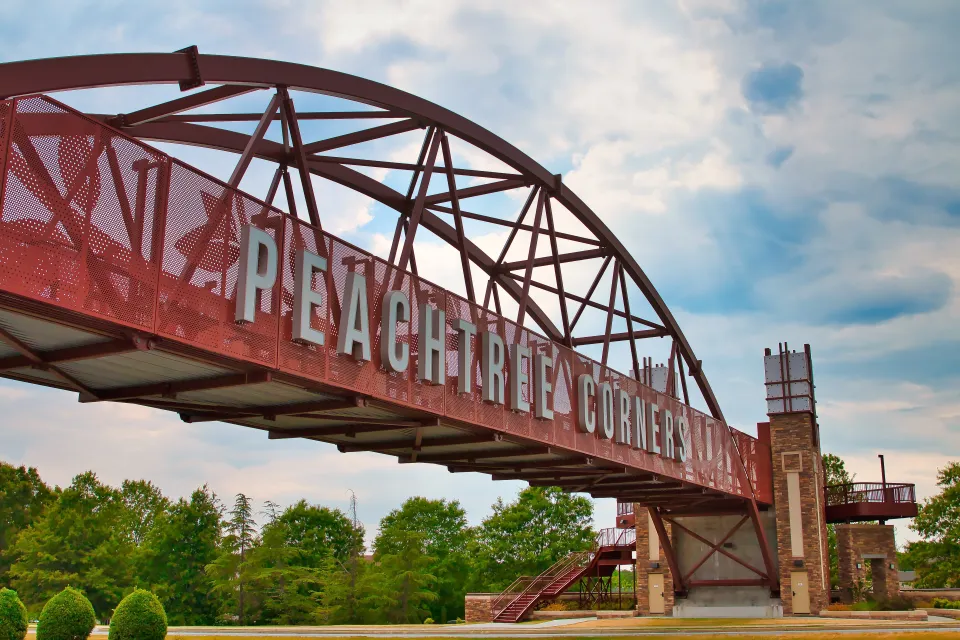 Red bridge with arches over highway with white letters spanning bridge "Peachtree Corners" near Atlanta, Georgia